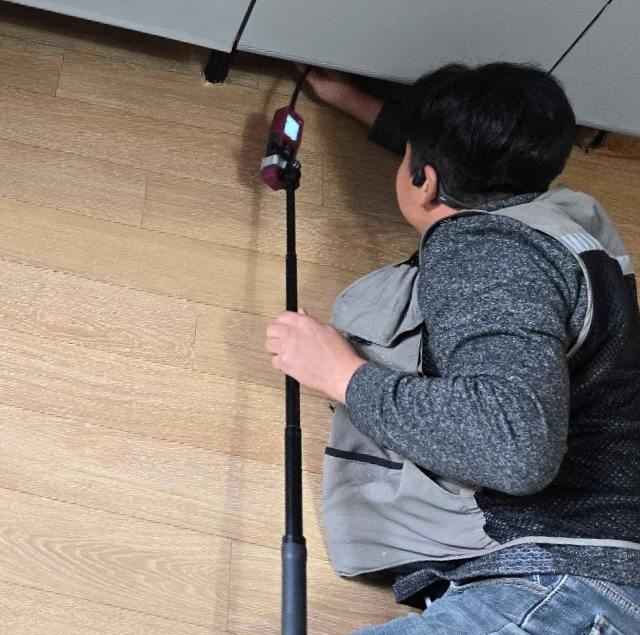 남양주 누수탐지 — 주방 바닥에 엎드려 청음 장비로 누수음을 듣는 기술자